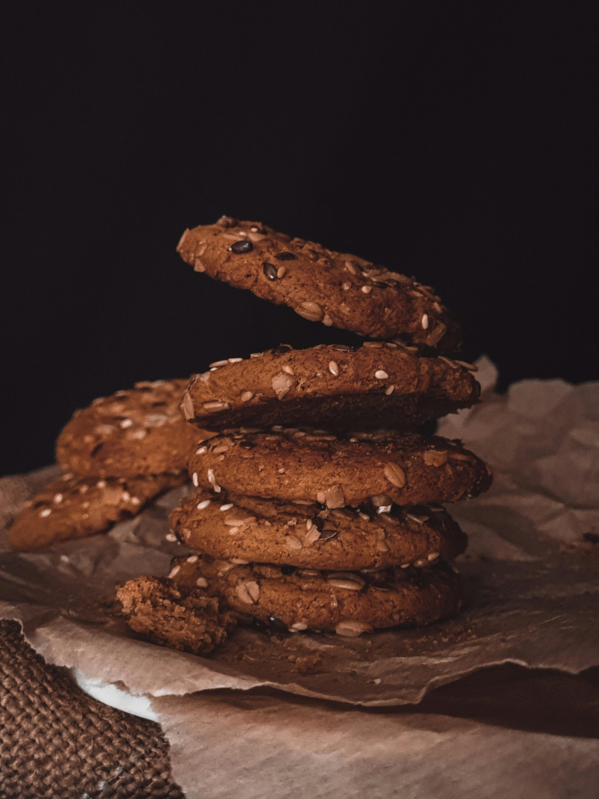 Delicious rustic cookies stacked on parchment, infused with seeds and nuts, perfect for dessert lovers.